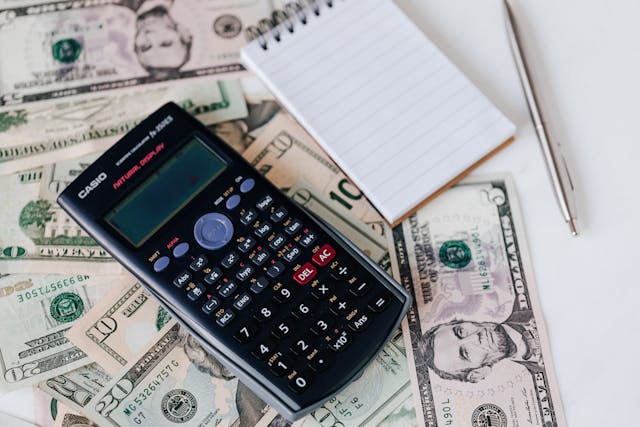 a calculator and notes pad resting on money