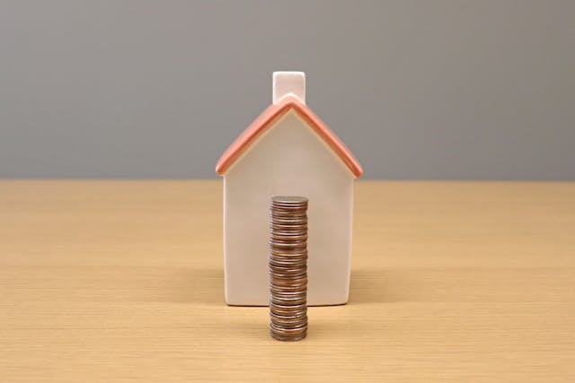 a house figurine behind a stack of coins